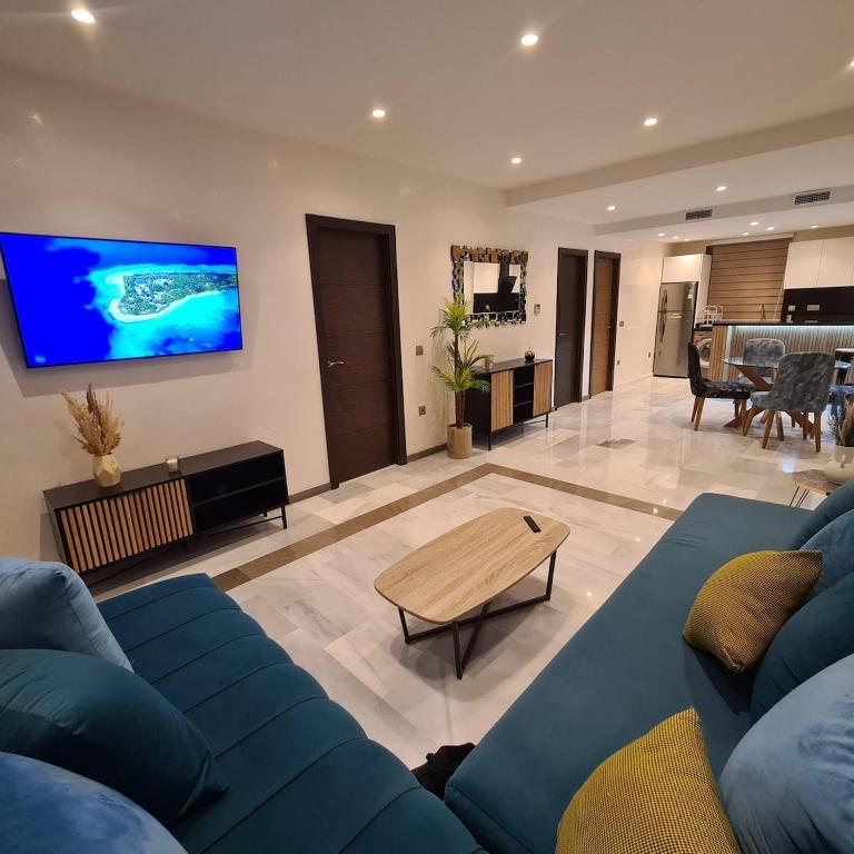 a living room with a blue couch and a tv at Appartement sur la corniche 2 chambres in Tangier