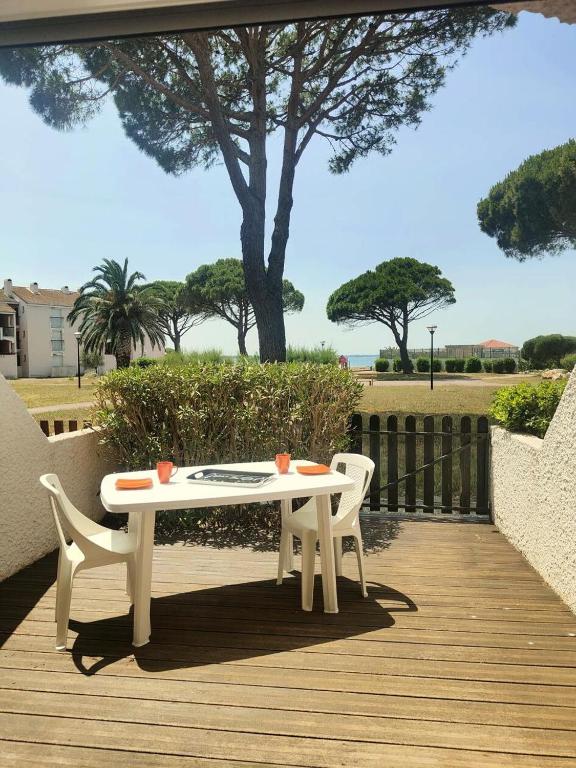 une table blanche et deux chaises sur une terrasse en bois dans l'établissement Résidence Antigua - Studio en rdc, vue sur parc ombragé et étang. Grande terrasse MAE-4463, au Barcarès