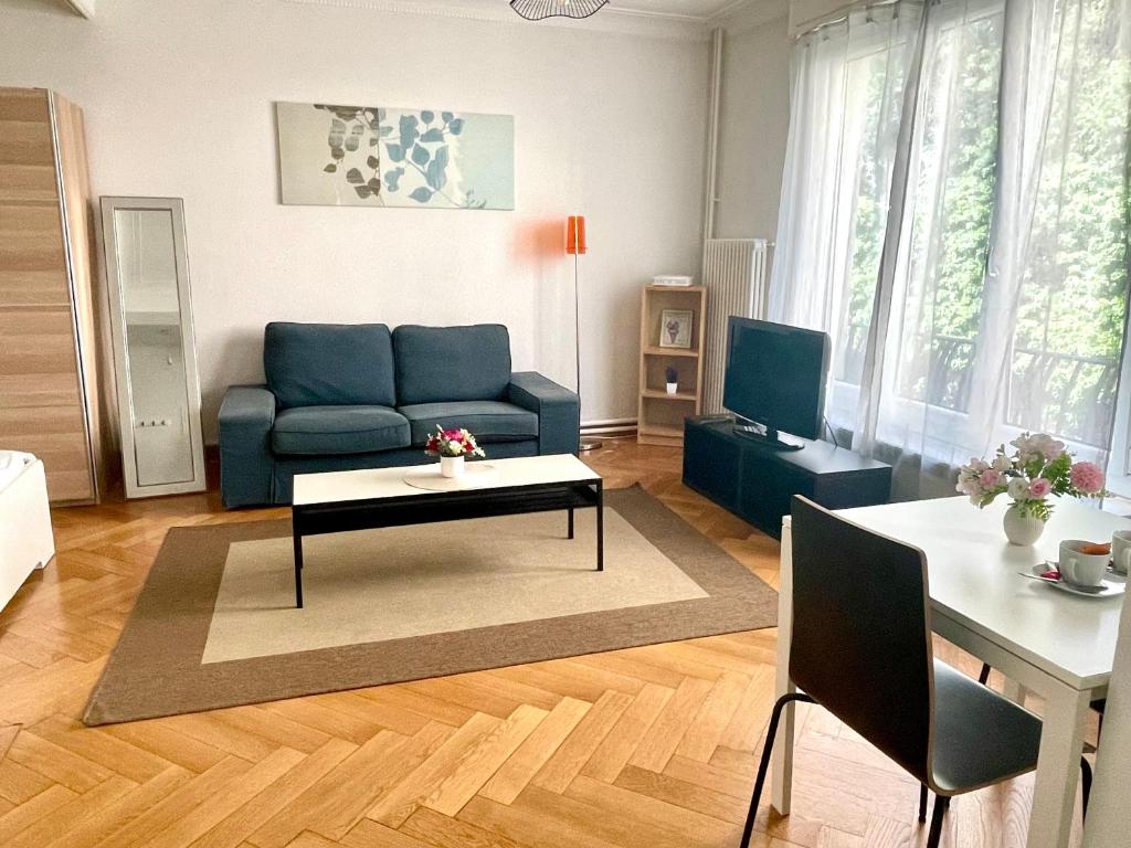 Una sala de estar con un sofá azul y una mesa. en Appartement meublé proche de la Gare de Lausanne 12, en Lausana