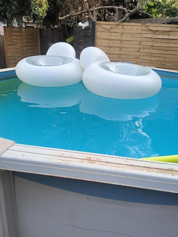 une piscine avec trois toilettes gonflables dans l'eau dans l'établissement L'oliveraie, à Marseille