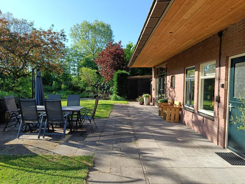 a patio with a table and chairs next to a house at Vakantiewoning met hottub en bedstede - De Kruidenhoeve in het Reestdal in Balkbrug