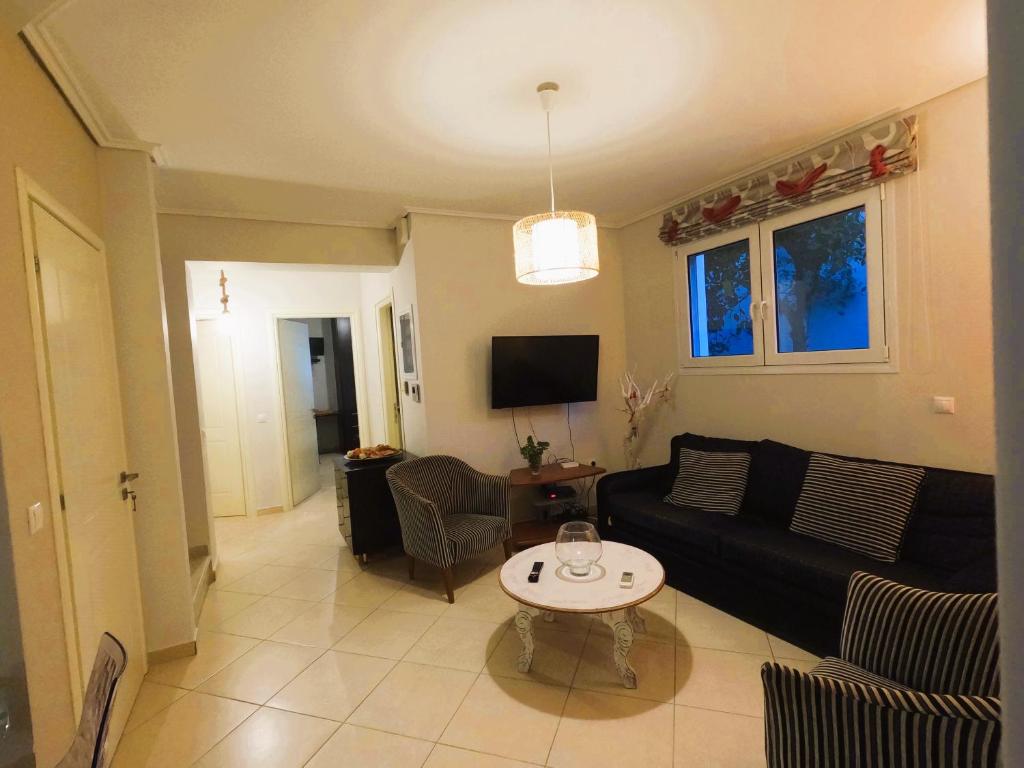 a living room with a black couch and a table at Stylish 2BR Semi-Basement- Cozy & Family-Friendly Retreat in Loutraki