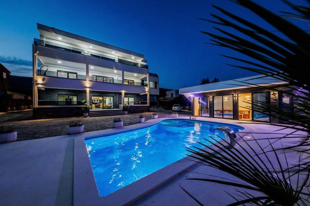 a large house with a swimming pool in front of it at VILLA Juky in Kaštela