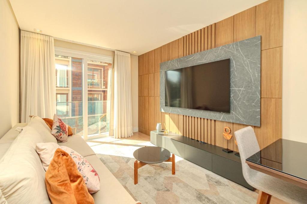 a living room with a couch and a television at Apto com Piscina Aquecida em Canela in Canela