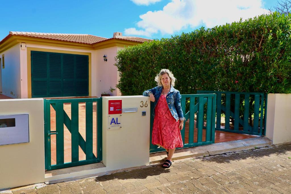 a woman standing next to a gate in front of a house at Casa das Ondas by AnaLodges in Porto Santo