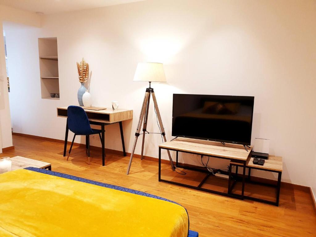 une chambre avec un lit et un bureau avec une télévision dans l'établissement Sadi Carnot - 1B Studio, à Millau