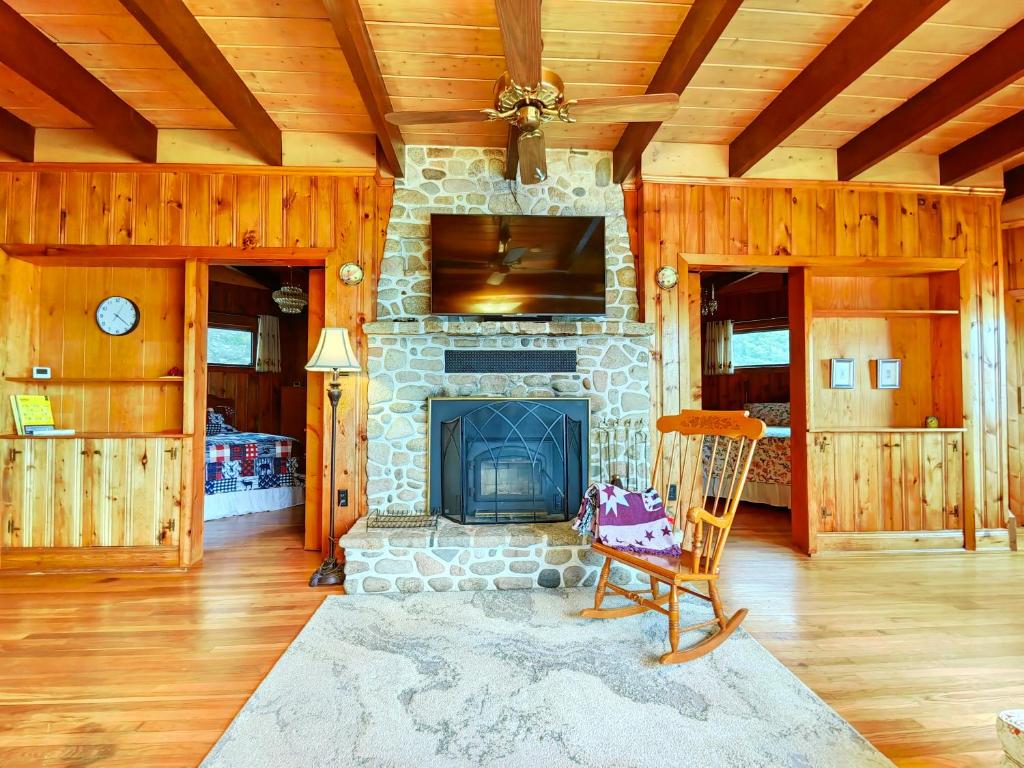 a living room with a stone fireplace and a wooden ceiling at 181 Oceanside Inn in Peggy's Cove