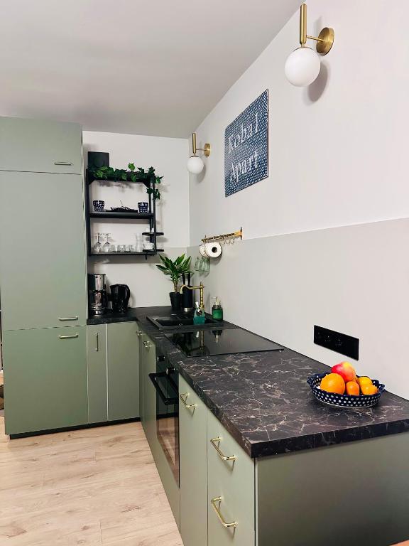 a kitchen with green cabinets and a bowl of fruit on a counter at Kobal Apart in Bolesławiec