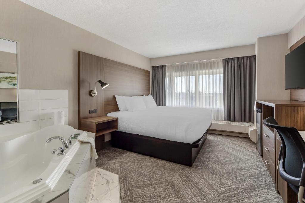 a hotel room with a bed and a bath tub at Best Western Cedar Park Inn in Edmonton