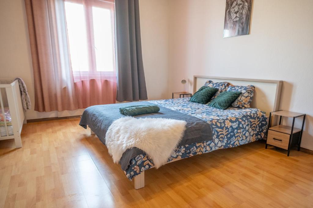 Un dormitorio con una cama con almohadas verdes y una ventana. en Harmony Appart FRANCE & SUISSE, en Saint-Louis