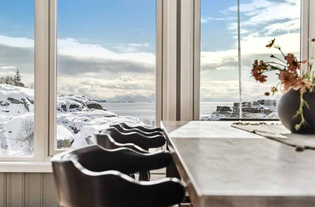 een keuken met een tafel en stoelen en een groot raam bij Hus i Lofoten in Kabelvåg