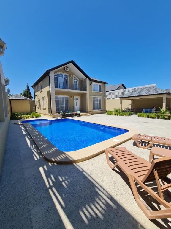 a swimming pool with two lounge chairs and a house at Gulu Cottage House in Mərdəkan