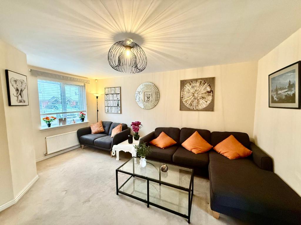 a living room with a black couch and a chandelier at Torwood Townhouse - SuperFast WiFi, Contractor Friendly with Free Parking in Edinburgh