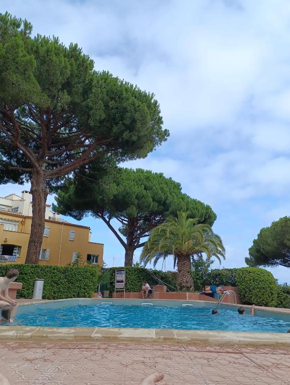 une piscine avec des arbres en arrière-plan dans l'établissement Résidence avec piscine sur quai avec bateau, au Cap d'Agde
