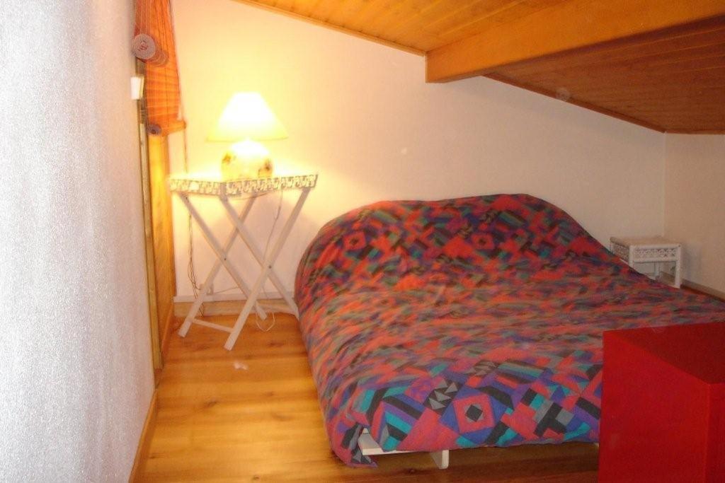 - une chambre avec un lit et une couverture colorée dans l'établissement Maison bois dans village vacances 8 personnes, à La Teste-de-Buch