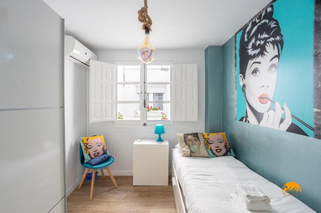 Una pequeña habitación con una cama y una pared azul. en Alma gaditana en la caleta, en Cádiz