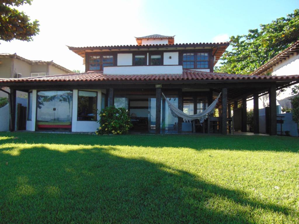 una casa con un césped verde delante de ella en Casa Buzios Frente ao Mar, en Búzios