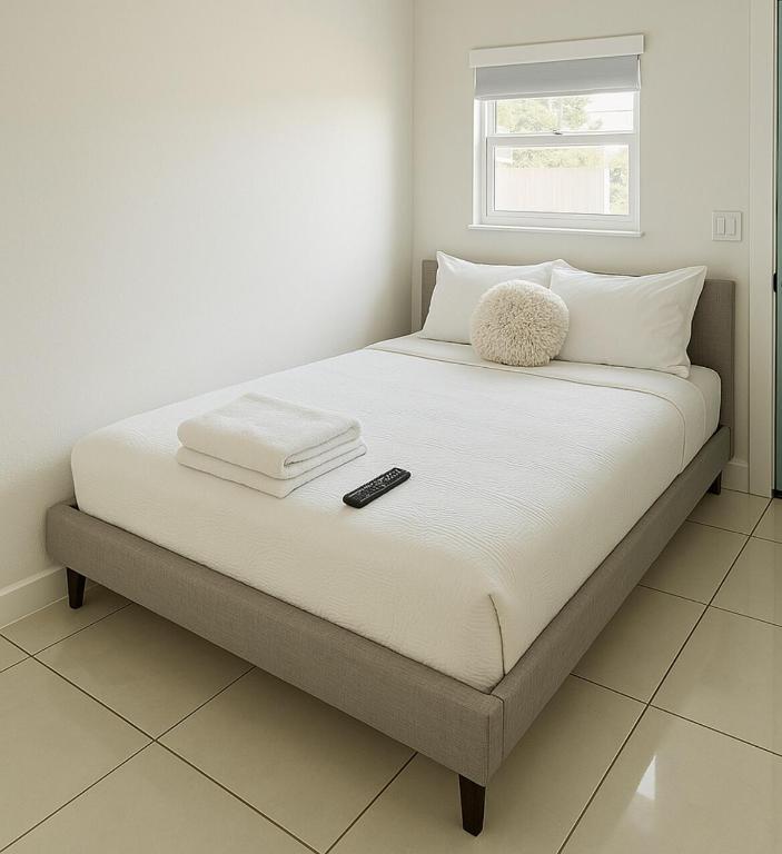 a bed with white sheets and a remote control on it at Tempurpedic Queen - Laundry, Parking & EV Charger in Hollywood