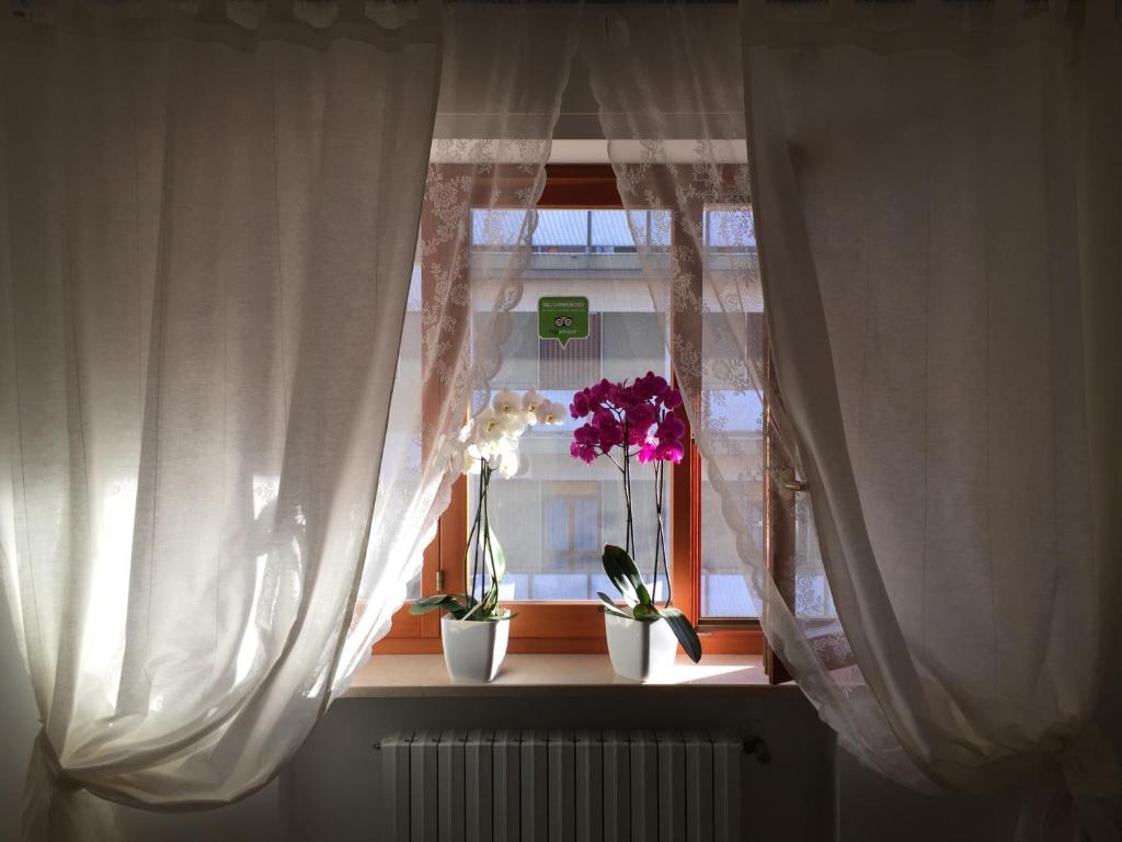 een raam met witte gordijnen en bloemen op een vensterbank bij B&B Le Saline in Taranto