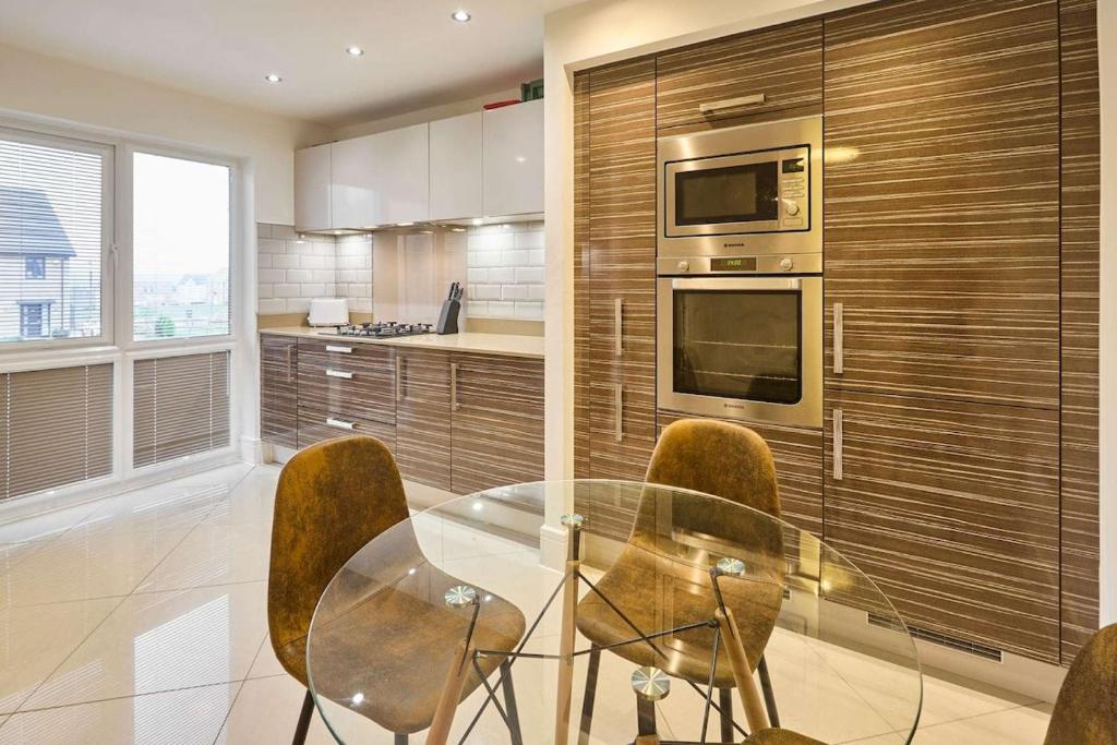 eine Küche mit einem Glastisch und einigen Stühlen in der Unterkunft Modern Home with Garden, Corby in Corby and Weldon
