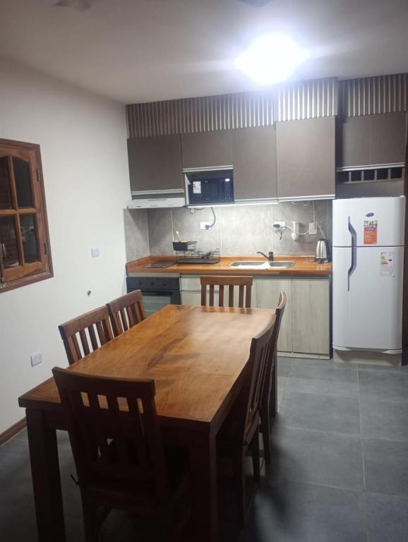 a kitchen with a wooden table and a refrigerator at Complejo Cerro Morado in Villa Unión