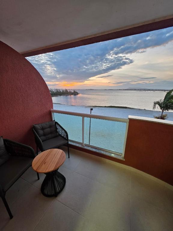 a balcony with a couch and a table and a view of the water at Apartamento em Arraial do Cabo in Arraial do Cabo