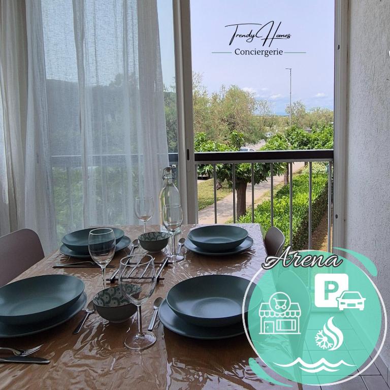 une table avec des assiettes noires et des verres à vin et une fenêtre dans l'établissement T2 Cozy a 2 min à pied des plages - Parking privé, à Palavas-les-Flots