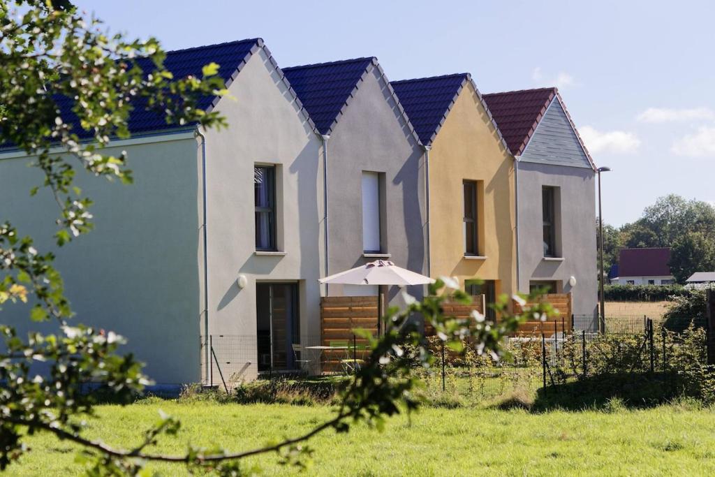 une rangée de maisons avec un parapluie dans un champ dans l'établissement Les pâquerettes, jardin, garage, parking gratuit, à Saint-Valery-sur-Somme