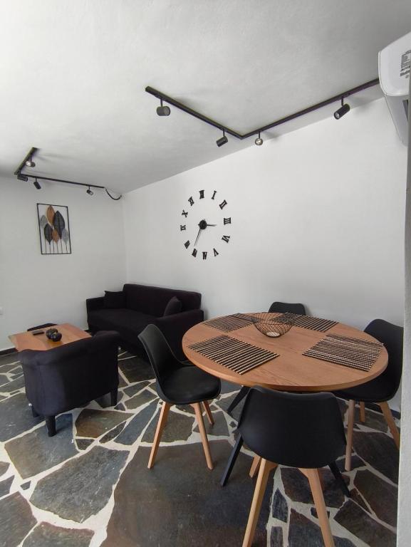 a living room with a table and chairs and a clock at MAGIA's HOUSE in Karistos