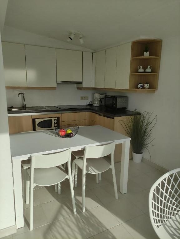 - une cuisine avec une table blanche et des chaises blanches dans l'établissement Appartement Iris, au Coq