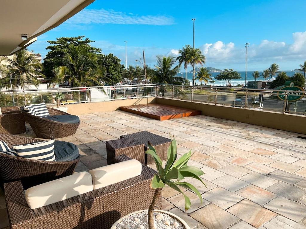 a patio with chairs and tables on a roof at Apto Barra da Tijuca - Beira Mar in Rio de Janeiro