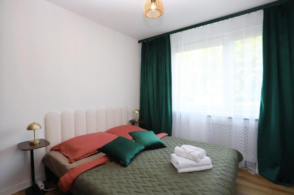 een slaapkamer met een bed met groene en rode kussens bij #PodZamek in Wałbrzych