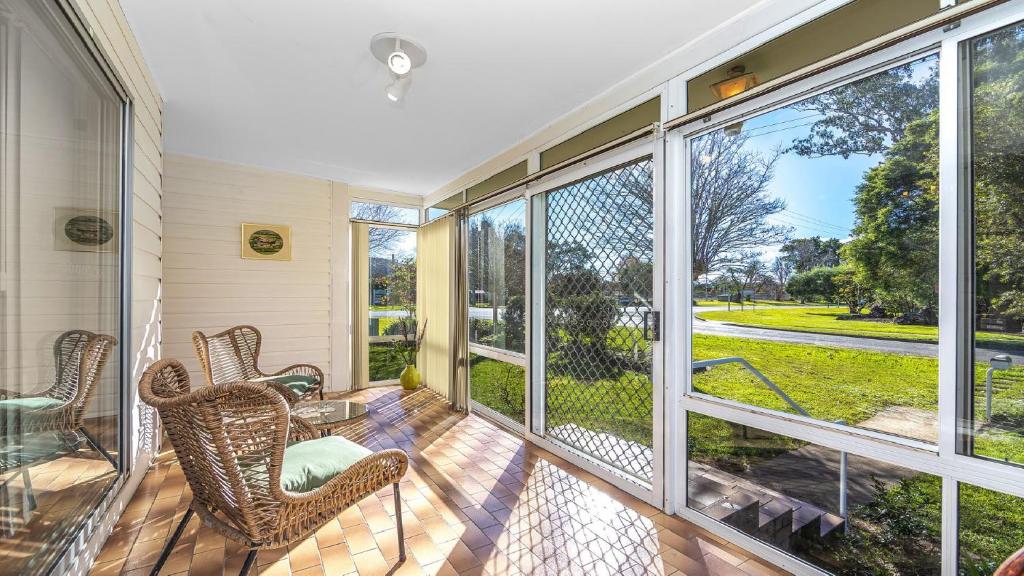 eine abgeschirmte Veranda mit Stühlen, Tischen und großen Fenstern in der Unterkunft Margarets Place - Character Filled Cottage In Heart Of Gloucester in Gloucester