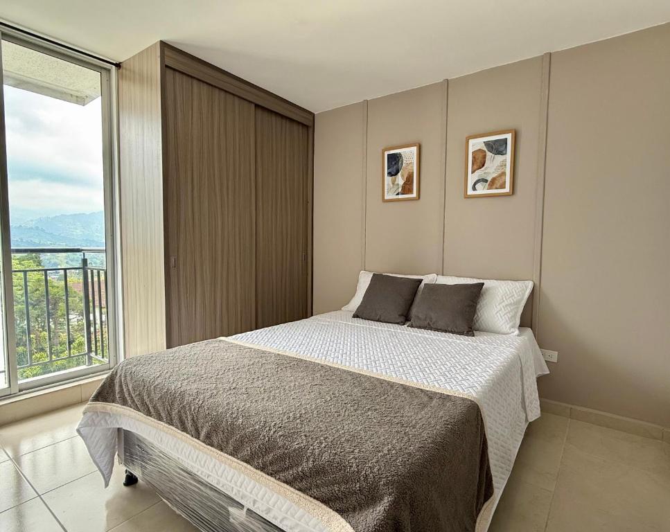 a bedroom with a bed and a large window at Acogedor Refugio Céntrico con Parking Privado in Armenia
