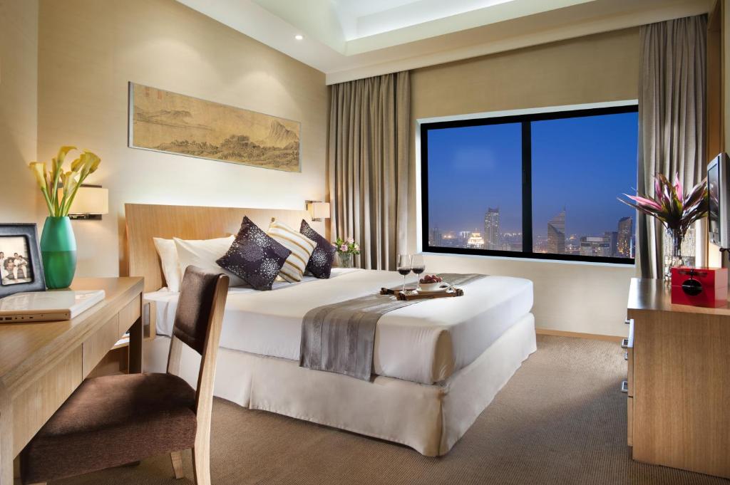 BinhaiにあるAscott TEDA MSD Tianjinのベッド、デスク、窓が備わるホテルルームです。