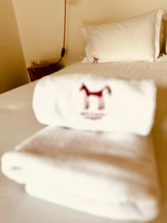 two beds with white towels and a red symbol on them at El Establo in Puerto Natales