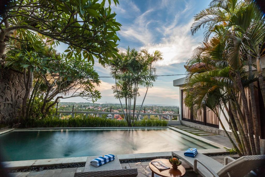 a swimming pool in a villa with palm trees at The Kawan Jimbaran in Jimbaran