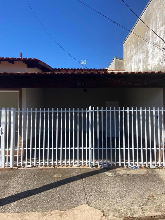 a white fence on the side of a house at Casa Aconchegante Alfenas in Alfenas