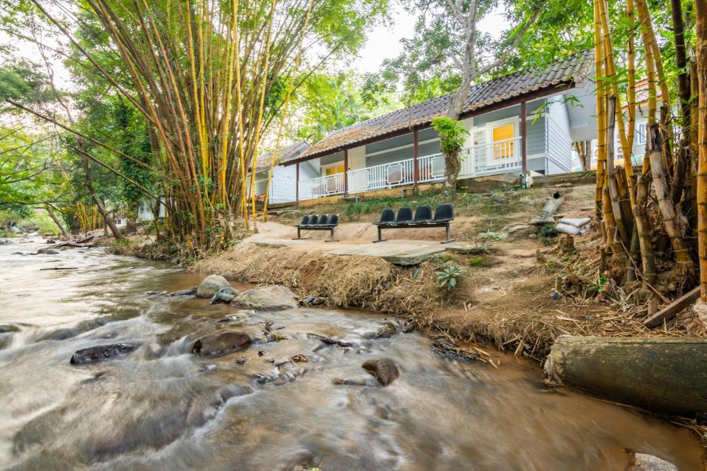 a house with two chairs sitting next to a river at Rinrada Resort in Ban Mae Mae