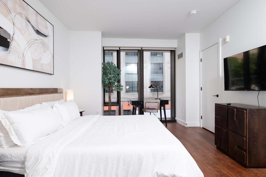 a white bedroom with a large bed and a table at Back-Bay Upscale Central Condo Rooftop & Parking in Boston