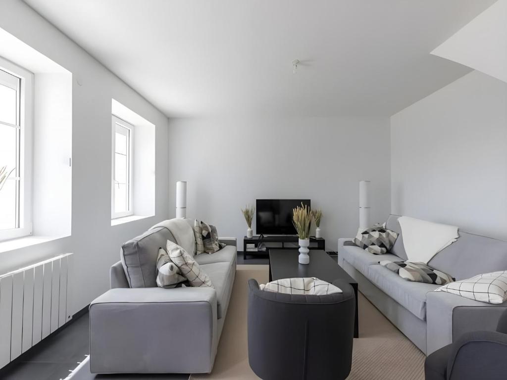 - un salon blanc avec deux canapés et une télévision dans l'établissement Farmhouse in Laigné near Le Mans Circuit, à Laigné-en-Belin