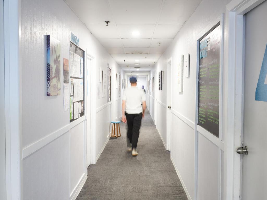 Un uomo che cammina lungo un corridoio in un corridoio dell'ospedale di Attic Backpackers ad Auckland
