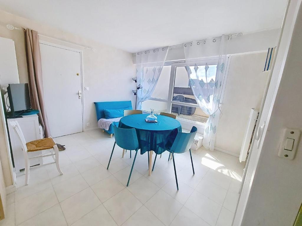 une salle à manger avec une table et des chaises bleues dans l'établissement Appartement 4 personnes près de la mer avec terrasse et parking - FR-1-746-34, à Courseulles-sur-Mer