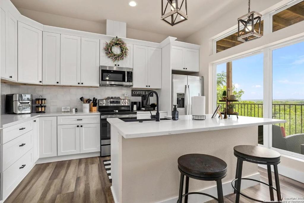 a kitchen with white cabinets and a counter with stools at Riverscape Townhome B, Steps to Gruene Hall! in New Braunfels