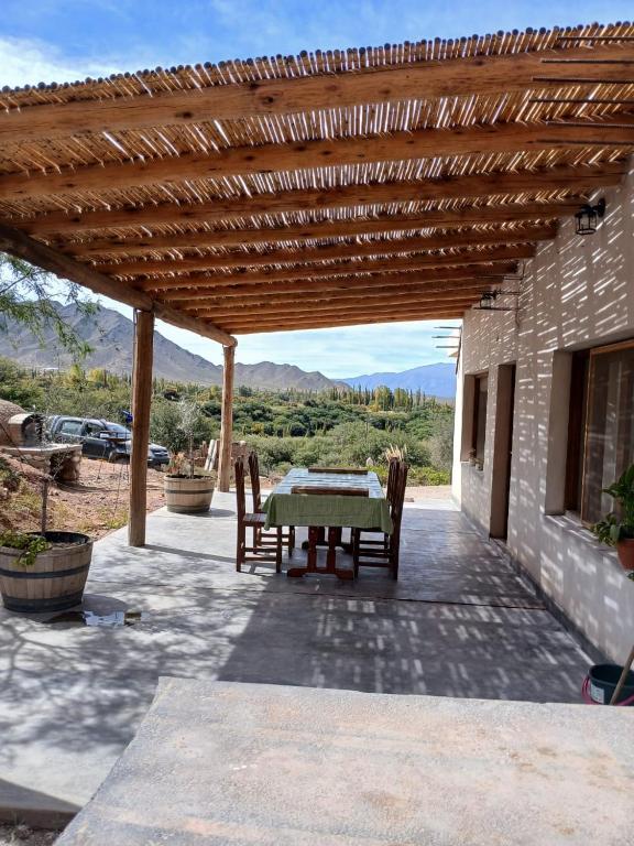 a patio with a table and chairs under a wooden pergola at Casa Florencia in Cachí