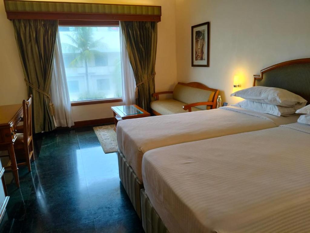 a hotel room with two beds and a window at The Ummed Ahmedabad Airport in Ahmedabad