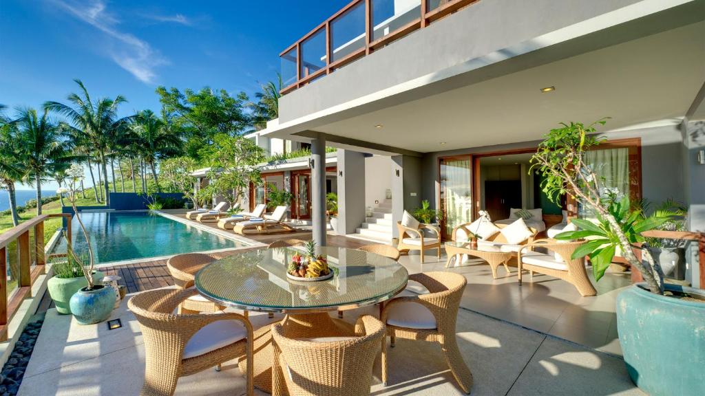 an outdoor patio with a table and chairs and a pool at Malimbu Cliff Villa by Elite Havens in Senggigi