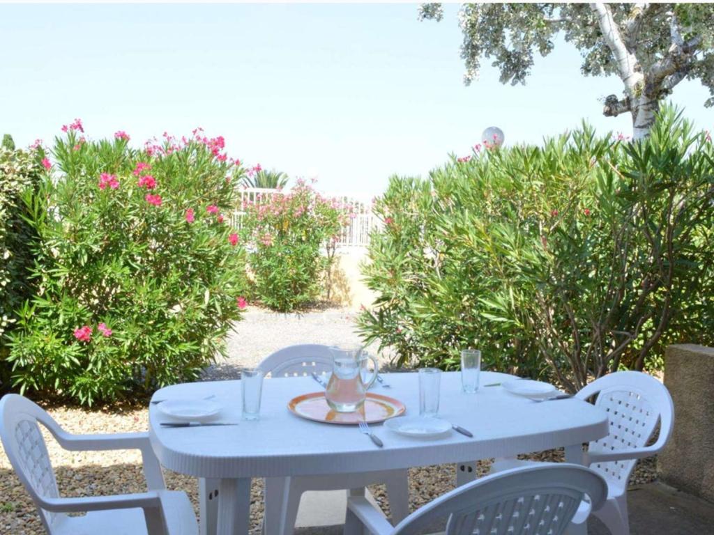 une table blanche et des chaises avec une table et des fleurs dans l'établissement Pavillon 3 pièces avec terrasse, près de la plage - FR-1-229B-112, à Narbonne