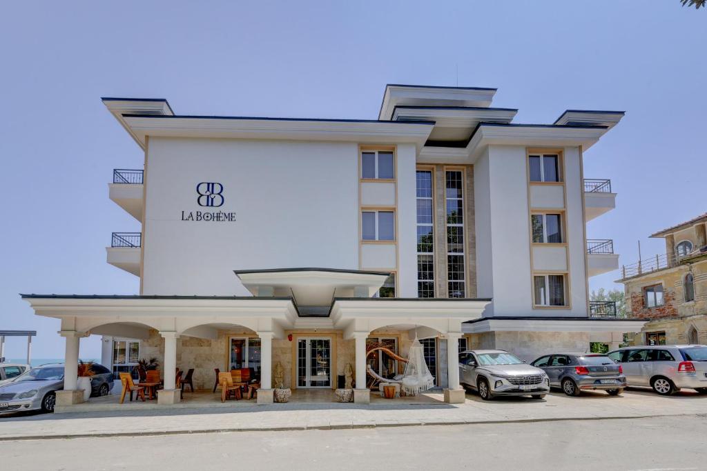 a large white building with cars parked in a parking lot at La Boheme - Adults Only in Obzor
