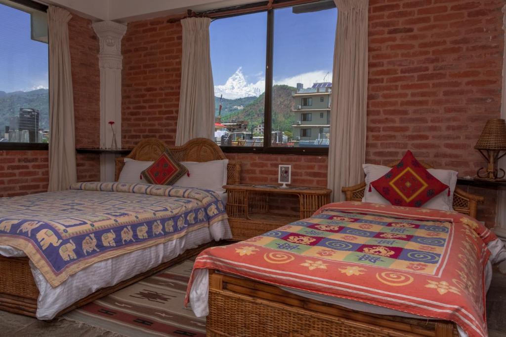 due letti in una stanza con una grande finestra di Peace Eye Guest House a Pokhara